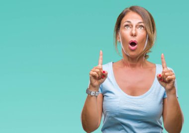 İspanyol kadın kıdemli orta yaş izole arka plan üzerinden hayran ve yukarıya bakıp parmakları ile işaret şaşırttı ve silah kaldırdı.