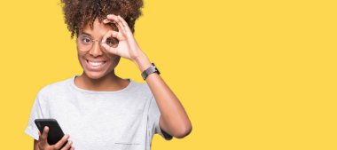 Mutlu yüz el parmaklarının arasından seyir göz üzerinde ok işaretiyle yapıyor gülümseyen izole arka plan üzerinde akıllı telefon kullanan genç Afro-Amerikan kadın