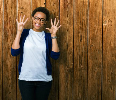 Genç güzel Afrikalı-Amerikalı kadın gözlük gösterilen ve parmakları ile işaret izole arka plan üzerinde dokuz kendinden emin ve mutlu gülümseyerek iken numara.