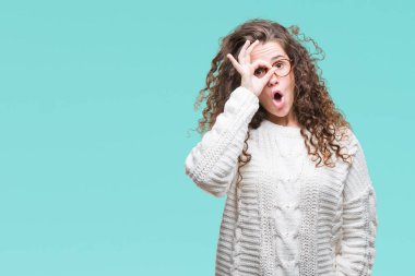 Güzel esmer kıvırcık saçlı Genç kız ok jest sürpriz yüz, göz parmaklarının arasından seyir şok yapıyor izole arka plan üzerinde kış kazak giyiyor. İmansız ifade.