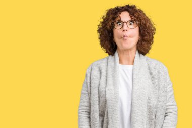 Ceket ve gözlük izole arka plan yapma balık yüzüne dudaklı, çılgın ve komik bir jest giyen güzel orta ager üst düzey kadın. Komik ifade.