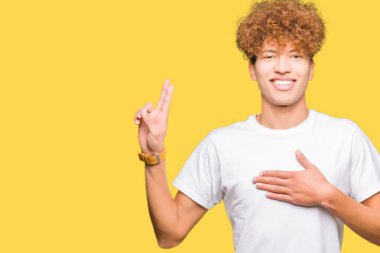 Afro saçlı bir sadakat sözü yemin yapma rahat beyaz t-shirt Swearing göğüs ve parmaklar, el ile giyen genç yakışıklı adam
