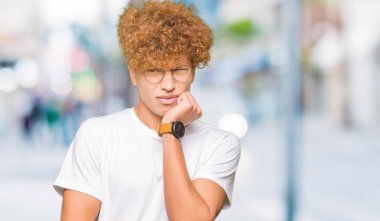 Yakışıklı genç afro saçlı gözlüklü stresli ve gergin elle çivi ısırma ağzına bakıyor. Anksiyete sorunu.