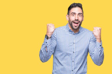 İzole arka plan kutlama üzerinde genç yakışıklı adam şaşırttı ve başarı için kaldırdı kollarını açarak hayret ve gözleri açık. Kazanan kavramı.