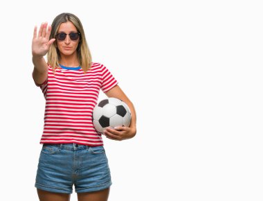 Açık eliyle dur işareti ile ciddi ve kendine güvenen ifade, savunma jest yapıyor izole arka plan üzerinde futbol futbol topu tutan genç güzel kadın