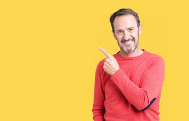 Yakışıklı orta yaş ağarmış komuta sizde izole arka neşeli bir gülümseme ile yüz el ve parmak kadar mutlu ve doğal ifade yüzünde yanında işaret içinde kış kazak giyiyor