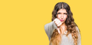 Kış elbise mutsuz ve kızgın gösteren ret arıyorsunuz ve başparmak aşağı hareketi ile negatif giyen genç güzel kadın. Kötü ifade.