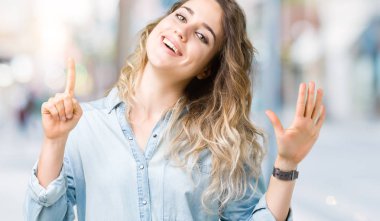 Gösterilen ve parmakları ile işaret izole arka plan üzerinde sarışın güzel genç kadın kendinden emin ve mutlu gülümseyerek süre 6 numara.