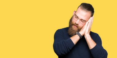 Genç Sarışın adamın gözlük ve balıkçı yaka kazak uyku giydiğini hayal ve elleri ile kapalı gözler gülümseyen birlikte poz yorgun.