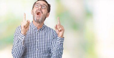 Yakışıklı orta yaş zarif üst düzey iş adamı izole arka plan üzerinde gözlük hayrete ve yukarıya bakıyor ve parmakları ile işaret ve silah kaldırdı şaşırttı.