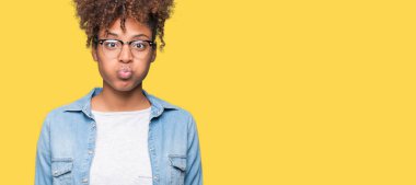 Komik surat ile yanakları şişirme izole arka plan üzerinde gözlük güzel genç Afro-Amerikan kadın. Ağız ile hava, deli ifade şişirilmiş.