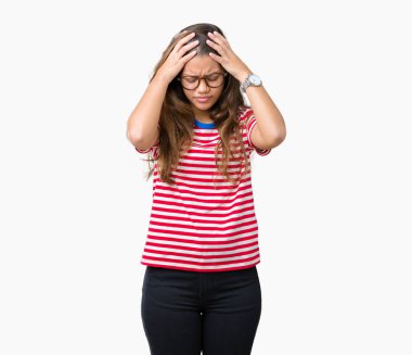 Giyen genç güzel esmer kadın gözlük ve t-shirt çünkü umutsuz ve stresli baş ağrısı acı izole arka plan üzerinde çizgili ağrı ve migren. Ellerini kafasına.