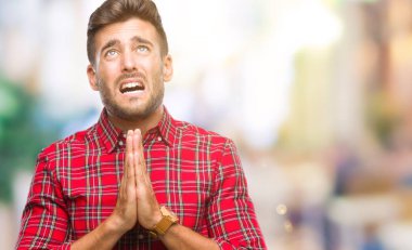 Yakışıklı delikanlı yalvarıyor ve umut ifade yüzünde çok duygusal ve endişe ile birlikte elleriyle dua izole arka plan üzerinde. Bağışlanmak. Din kavramı.