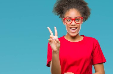 Mutlu yüz zafer işareti yaparken kameraya göz kırpıyor ile gülümseyen izole arka plan üzerinde gözlük takan genç afro Amerikalı kadın. İki numaralı.