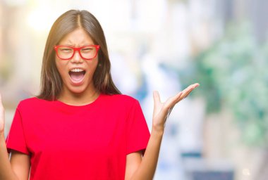 Üzerinde gözlük takan Genç Asyalı kadın arka plan deli izole ve deli bağırarak ve agresif ifade ve silah kaldırdı bağırıyor. Hayal kırıklığı kavramı.