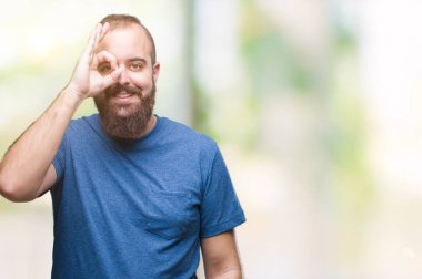 Genç beyaz hipster adam gülümsüyor, parmakları ile mutlu yüz üzerinden seyir göz el ile ok jest yapıyor izole arka plan.