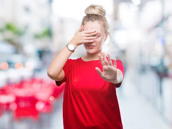 Young blonde woman wearing glasses over isolated background covering eyes with hands and doing stop gesture with sad and fear expression. Embarrassed and negative concept.