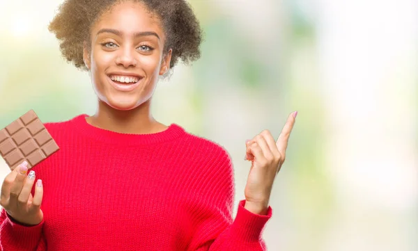 Junge Afroamerikanerin Isst Schokoriegel Über Isoliertem Hintergrund Sehr Glücklich Zeigt — Stockfoto