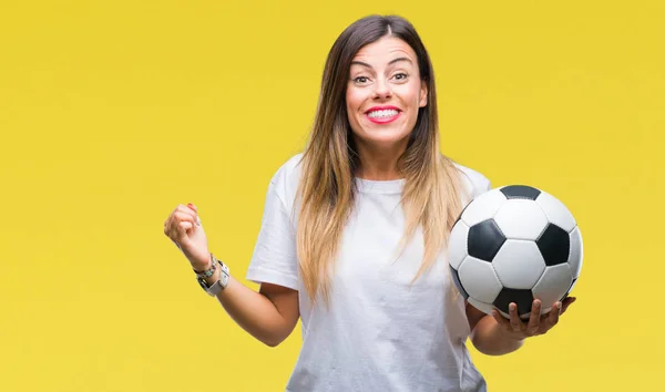 Young beautiful woman holding soccer ball over isolated background screaming proud and celebrating victory and success very excited, cheering emotion