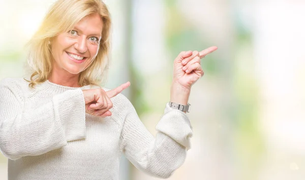 冬のセーターを着て中年金髪女性分離笑顔で側に つの手と指で指しているカメラ目線の背景 — ストック写真