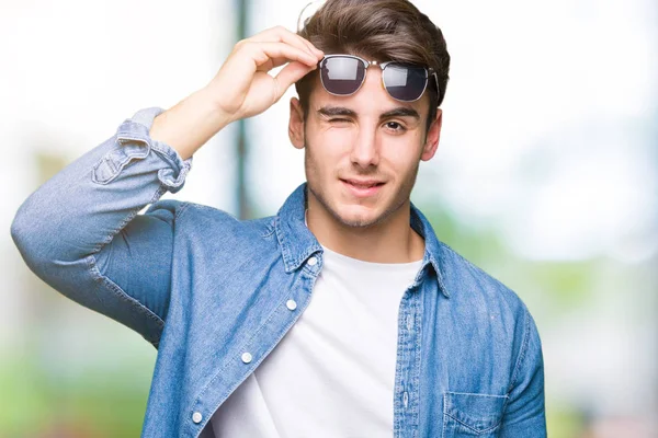 Jovem Homem Bonito Usando Óculos Sol Sobre Fundo Isolado Piscando — Fotografia de Stock