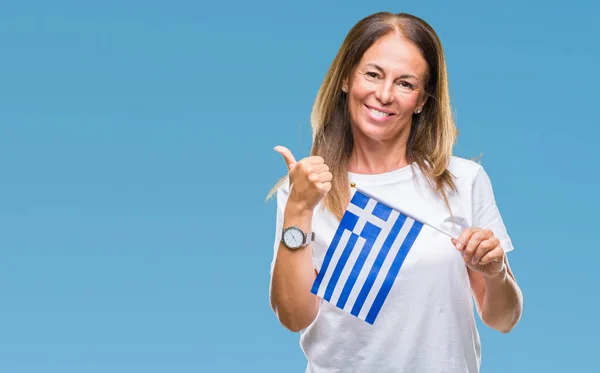 中年西班牙妇女拿着希腊的旗帜在孤立的背景高兴与灿烂的微笑做确定的标志 用手指竖起大拇指 优秀的标志 — 图库照片