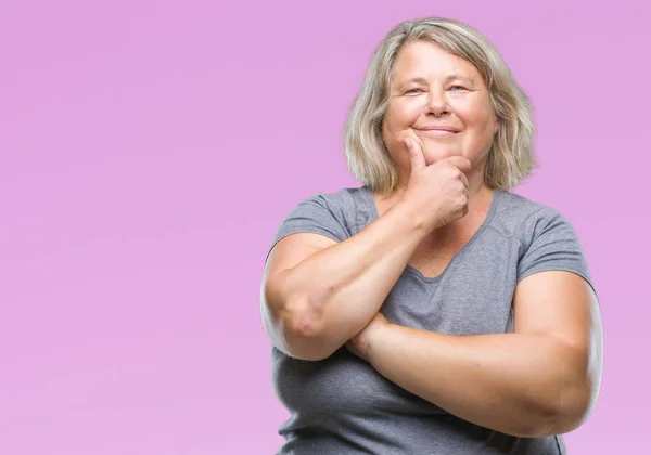 Senior plus size caucasian woman over isolated background looking confident at the camera with smile with crossed arms and hand raised on chin. Thinking positive.
