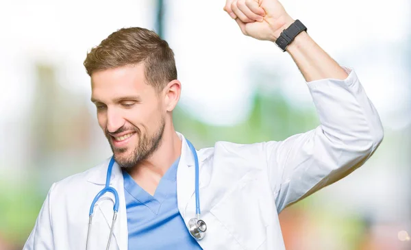 Handsome doctor man wearing medical uniform over isolated background Dancing happy and cheerful, smiling moving casual and confident listening to music