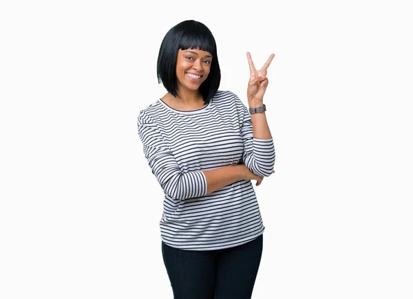 美しい若いアフリカ系アメリカ人女性の勝利のサインを行うカメラでウィンクしている幸せそうな顔を浮かべて隔離された背景にストライプのセーターを着ています — ストック写真