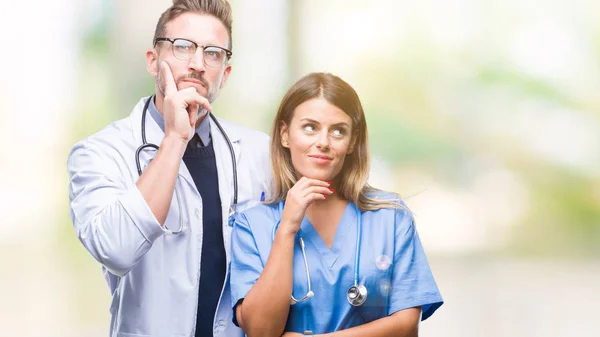 年轻夫妇的医生和外科医生在孤立的背景与手在下巴思考问题 沉思的表达 微笑着体贴的脸 怀疑概念 — 图库照片