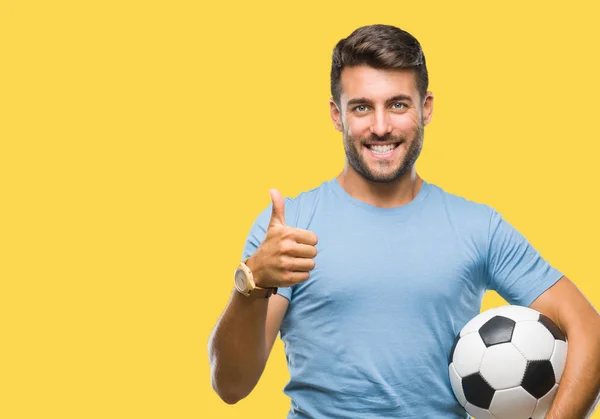 年轻英俊的男子举行足球足球在孤立的背景下高兴的大微笑做 拇指与手指 优秀的标志 — 图库照片