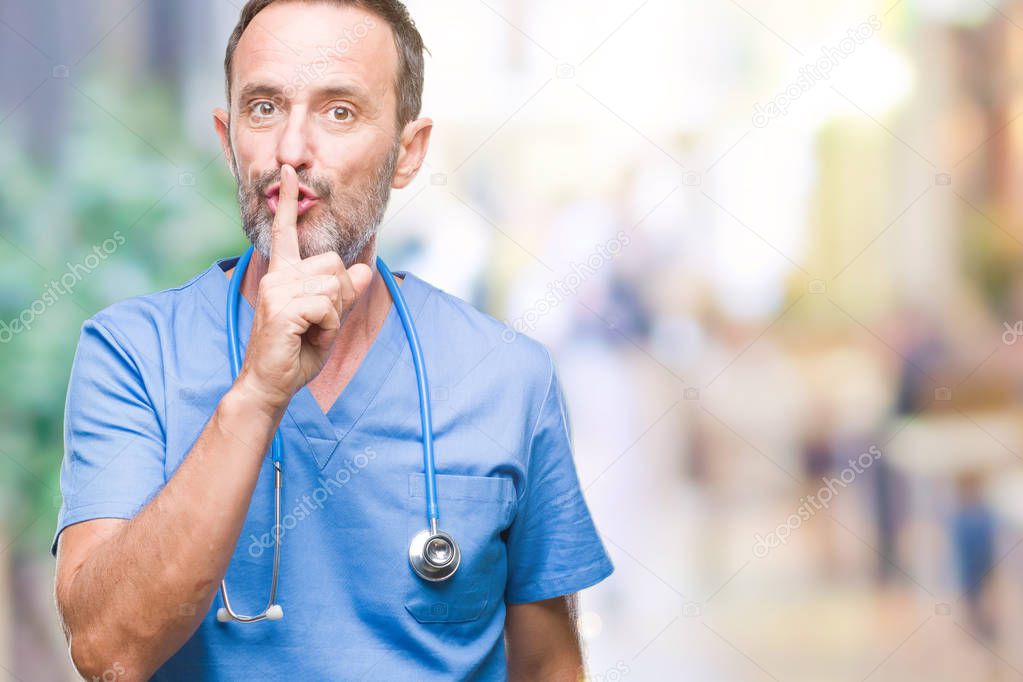 Middle age hoary senior doctor man wearing medical uniform over isolated background asking to be quiet with finger on lips. Silence and secret concept.