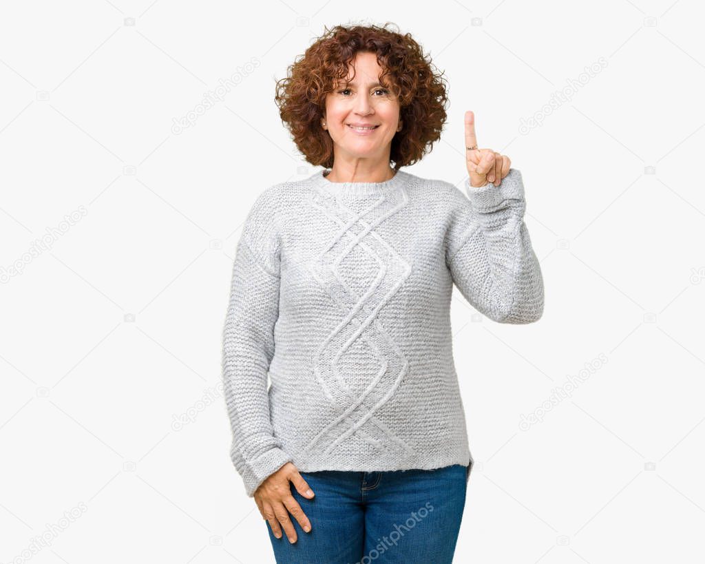 Beautiful middle ager senior woman wearing winter sweater over isolated background showing and pointing up with finger number one while smiling confident and happy.