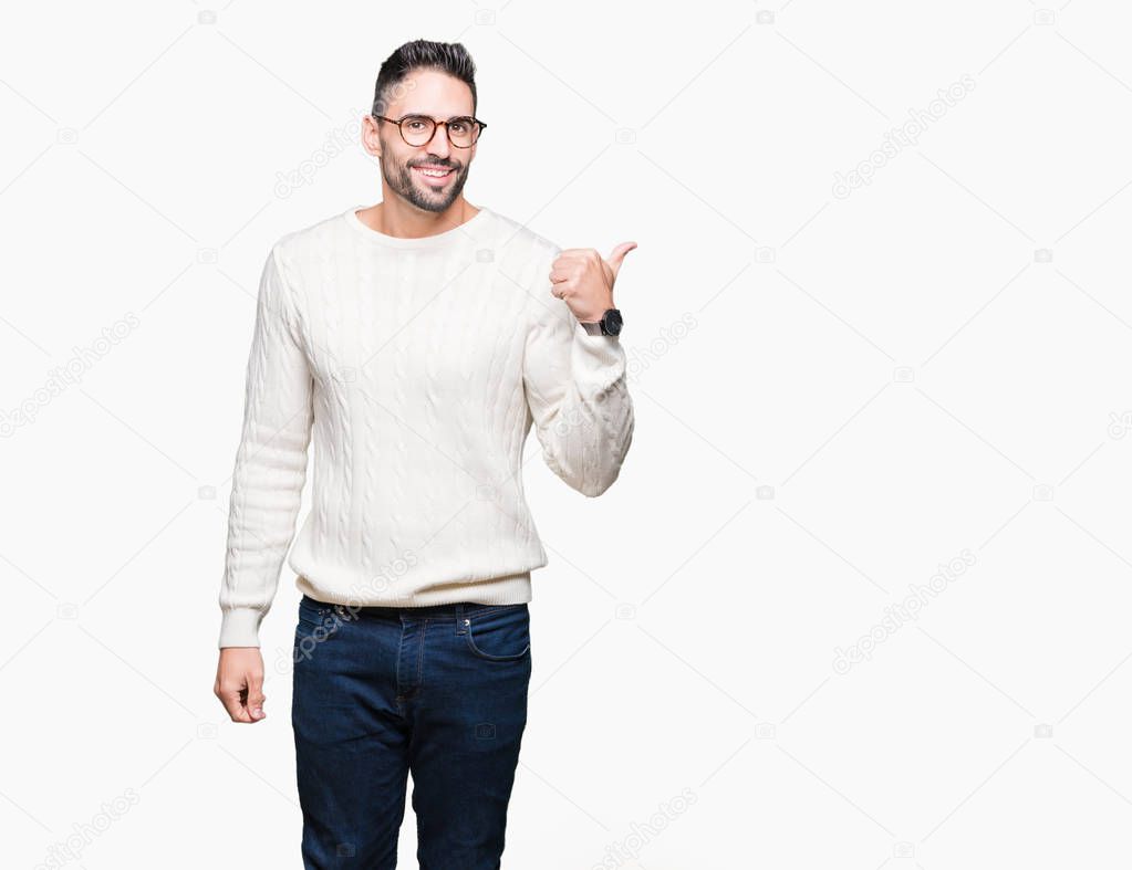 Young handsome man wearing glasses over isolated background smiling with happy face looking and pointing to the side with thumb up.
