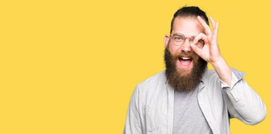 Genç sarışın adam gözlük gülümseyen, parmakları ile mutlu yüz üzerinden seyir göz el ile ok jest yapıyor.