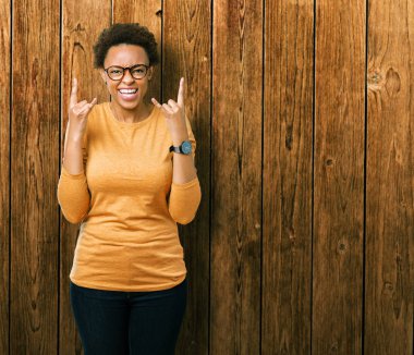 Deli ifade rock simge elle yapıyor ile bağırarak izole arka plan üzerinde gözlük takan genç güzel Afrikalı-Amerikalı kadın. Müzik yıldızı. Ağır kavramı.