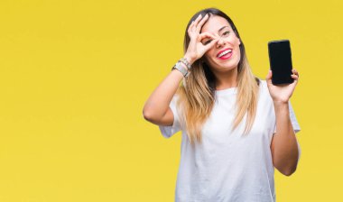 Genç güzel kadın gösteren boş ekran smartphone ile mutlu yüz el parmaklarının arasından seyir göz üzerinde ok işaretiyle yapıyor gülümseyen izole arka plan üzerinde