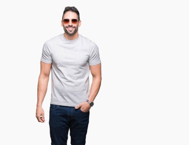 Genç yakışıklı adam yüzünde mutlu ve güzel bir gülümseme ile izole arka plan üzerinde güneş gözlüğü takıyor. Şanslı kişi.