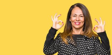 Güzel orta yaş kadın giyiyor moda ceket rahatla ve gülümseyen gözlerle kapalı parmak jestle meditasyon yapıyor. Yoga kavramı.