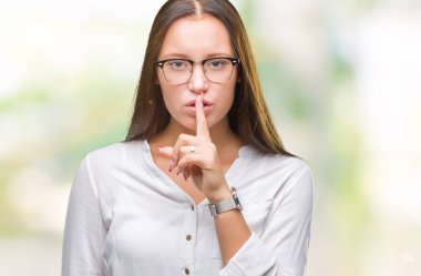 Dudaklarında parmak ile sessiz olmanı izole arka plan üzerinde gözlük takan Genç beyaz güzel iş kadını. Sessizlik ve gizli kavramı.