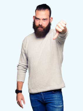 Genç sarışın adam mutsuz ve kızgın ret gösterilen ve başparmak aşağı hareketi ile negatif seyir sıradan kazak giyiyor. Kötü ifade.