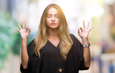 Genç güzel sarışın kadın izole arka plan üzerinde dinlenmek ve gülümseyen gözlerle parmak ile meditasyon jest yapıyor kapalı. Yoga kavramı.
