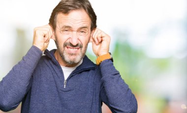 Orta yaş yakışıklı adamın gülen çekerek bir kazak giydiğini parmaklarıyla, komik jest kulaklar. Seçmelere sorun