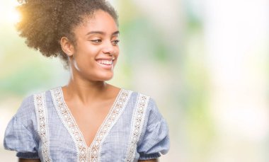 Uzak tarafına yüzünde, doğal ifade gülümseme ile seyir izole arka plan üzerinde genç afro Amerikalı kadın. Kendine güvenen gülüyor.