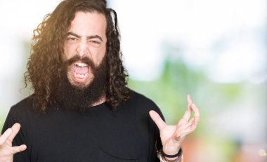 Uzun saç ve sakal takan ağır metal siyah kıyafet deli deli bağırarak ve agresif ifade ve silah kaldırdı bağırmaya genç adam. Hayal kırıklığı kavramı.