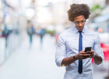 Afro Amerikalı iş adamı manifatura Smartphone akıllı yüzünde ciddi düşünme emin bir ifade ile izole arka plan üzerinde kullanma