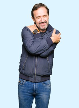 Orta yaş yakışıklı adam kendini mutlu ve olumlu sarılma, kendinden emin gülümseyen bir ceket giyiyor. Kendi aşk ve öz bakım