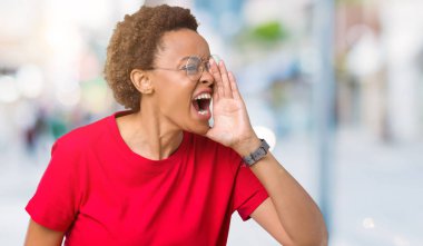 Bağırarak ve ağzı üzerinde el ile yan için çığlık izole arka plan üzerinde gözlük güzel genç Afro-Amerikan kadın. İletişim kavramı.