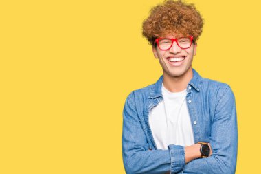 Afro saçlı ile gülümseyen bardakları mutlu yüz giyen genç yakışıklı adam kameraya seyir silah geçti. Olumlu bir kişi.