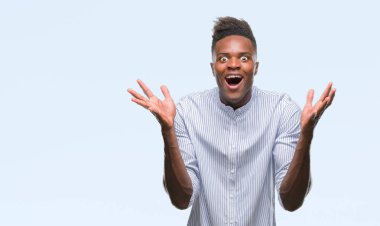 Afrikalı-Amerikalı genç deli kutluyor ve silah ile başarı için heyecanlı çığlık kaldırdı ve açık gözleri hayret izole arka plan üzerinde. Kazanan kavramı